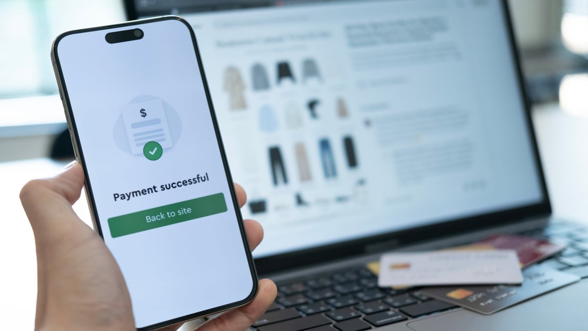 Holding a phone displaying a successful payment confirmation with a credit card below, highlighting convenient cashless payment